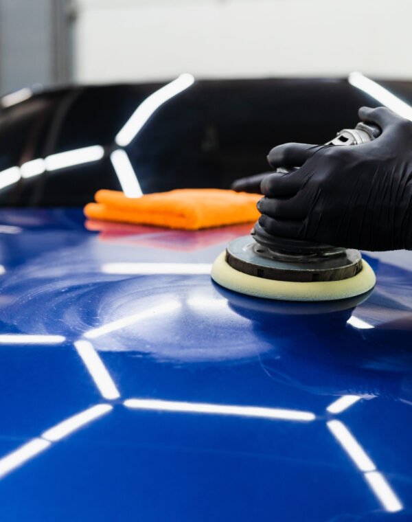 Car polishing with orbital polisher for remove scratches. Worker of detailing auto service making final polishing for car